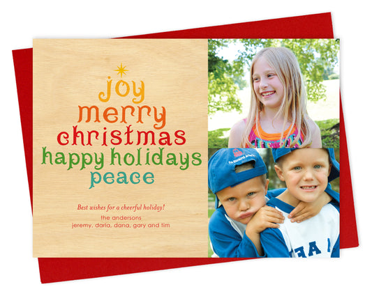 Customizable paper holiday card featuring your photo on the right and a colorful tree formed from the words “Joy, Merry Christmas, Happy Holidays, Peace,” with a personal greeting on a printed birch wood grain background on the left. Shown with a red envelope.