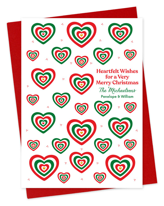 Customizable paper Christmas card with red and green heart patterns and a personal greeting on a white background. Shown with a red envelope.