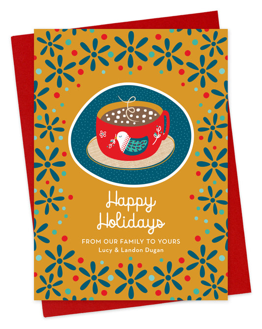 Front of paper holiday card featuring a mug of hot chocolate with a folk-style bird design, “Happy Holidays” text and a personal greeting on a festive patterned background. Shown with a red envelope.
