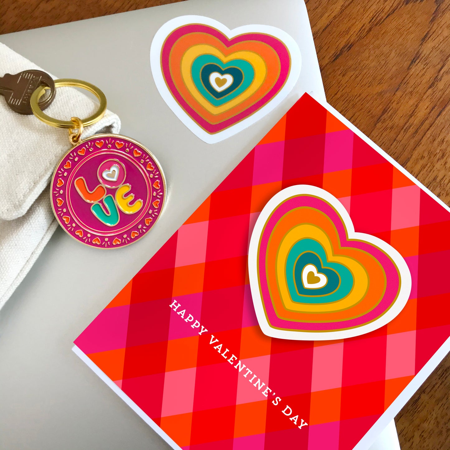 Colorful circle keychain with hearts bordering the word LOVE, vibrant radiating heart sticker, and Valentine's Day card with removable heart sticker