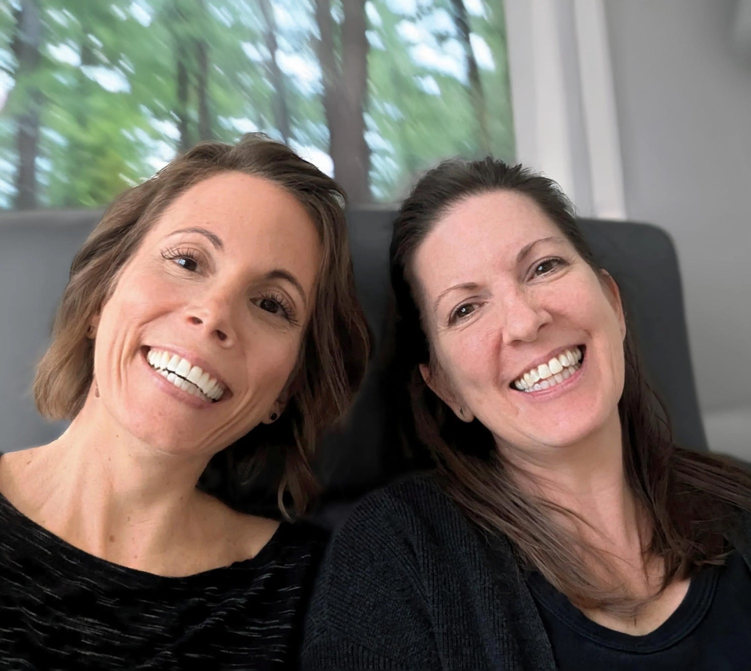 Jen and Meg smiling near a forest