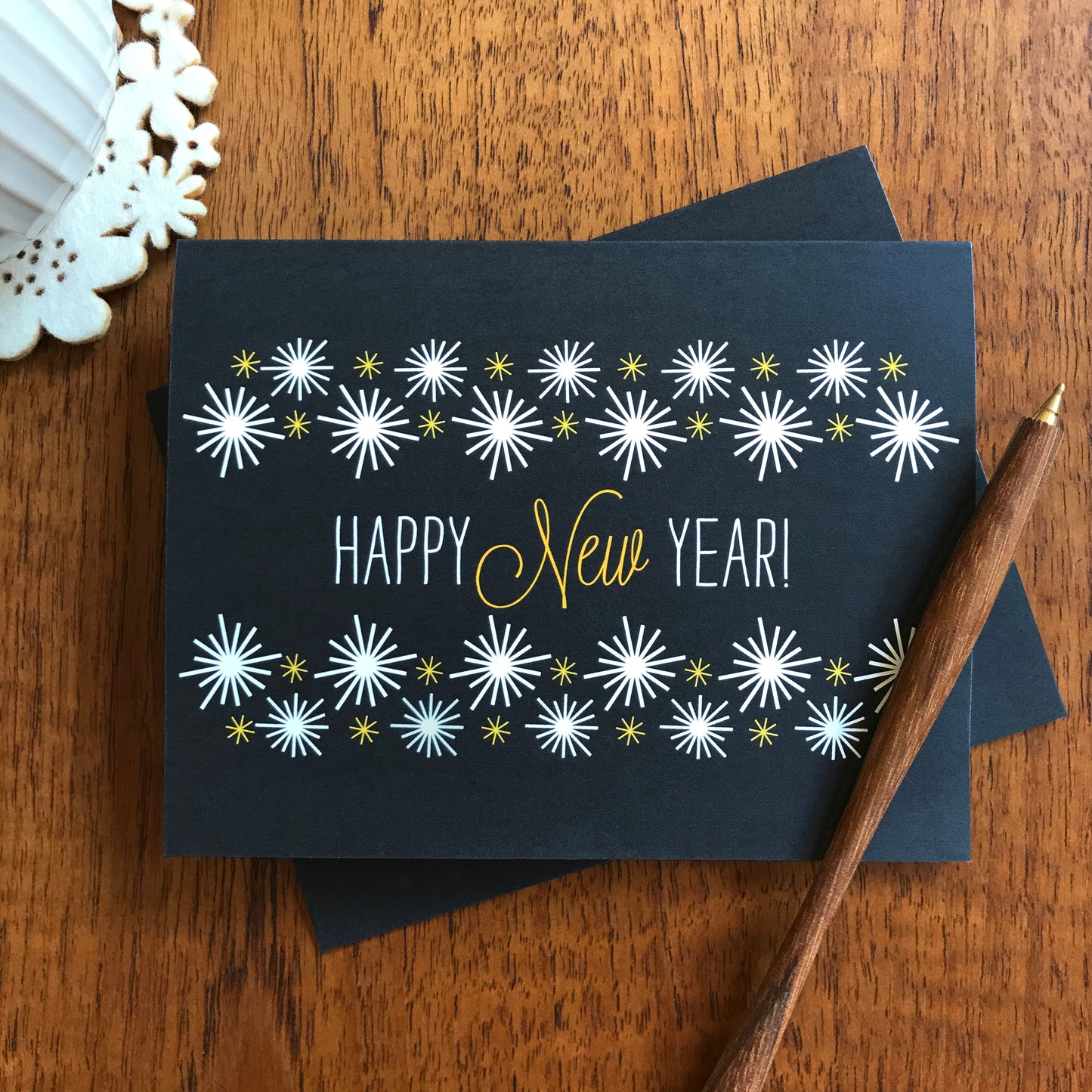 Black New Year's Card with white star bursts and wood pen