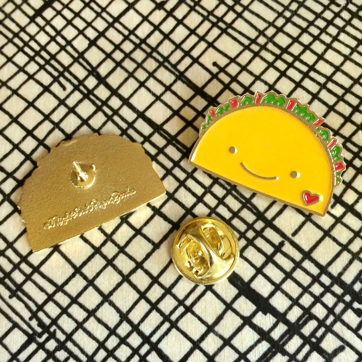 Taco enamel pin with simple smile face and small heart. Photo shows front and back of pin with 'Night Owl Paper Goods' logo.