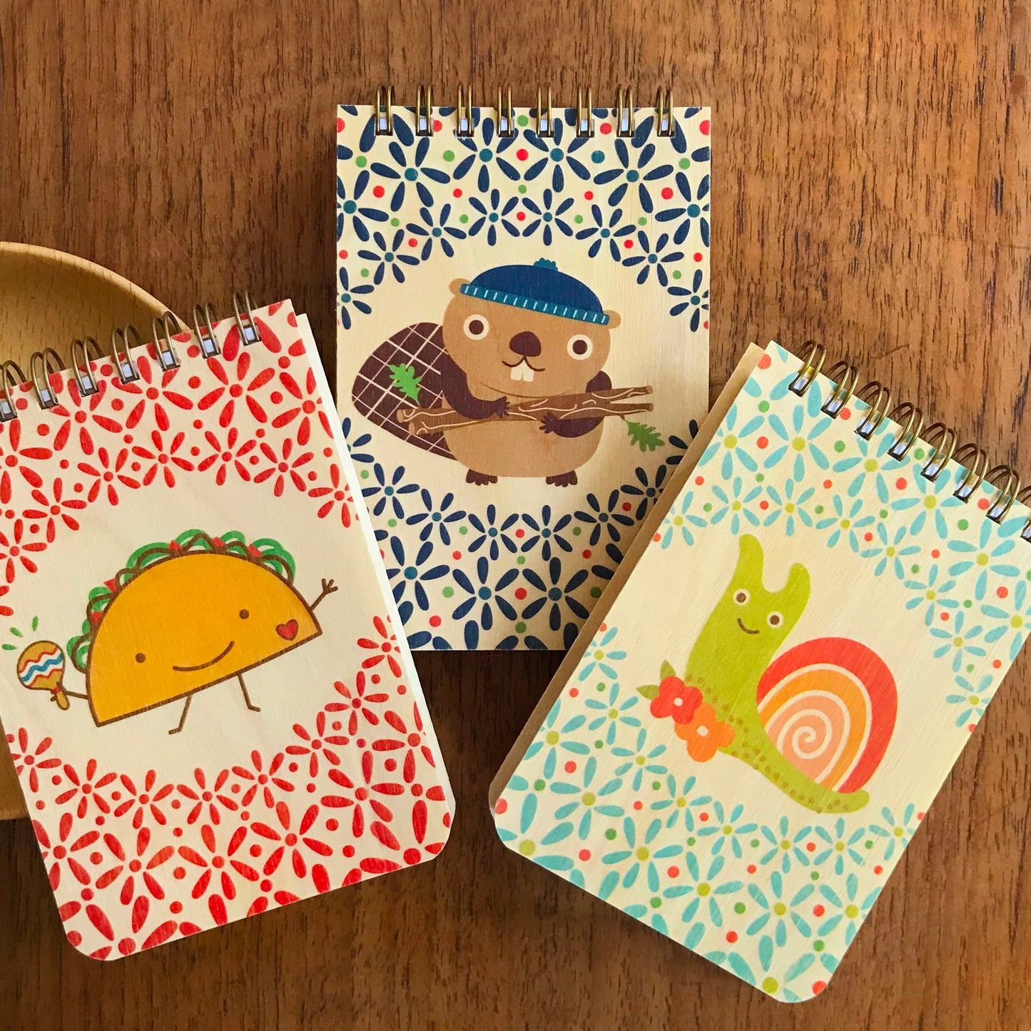 Three wood mini notepads featuring a taco, a beaver and a snail.