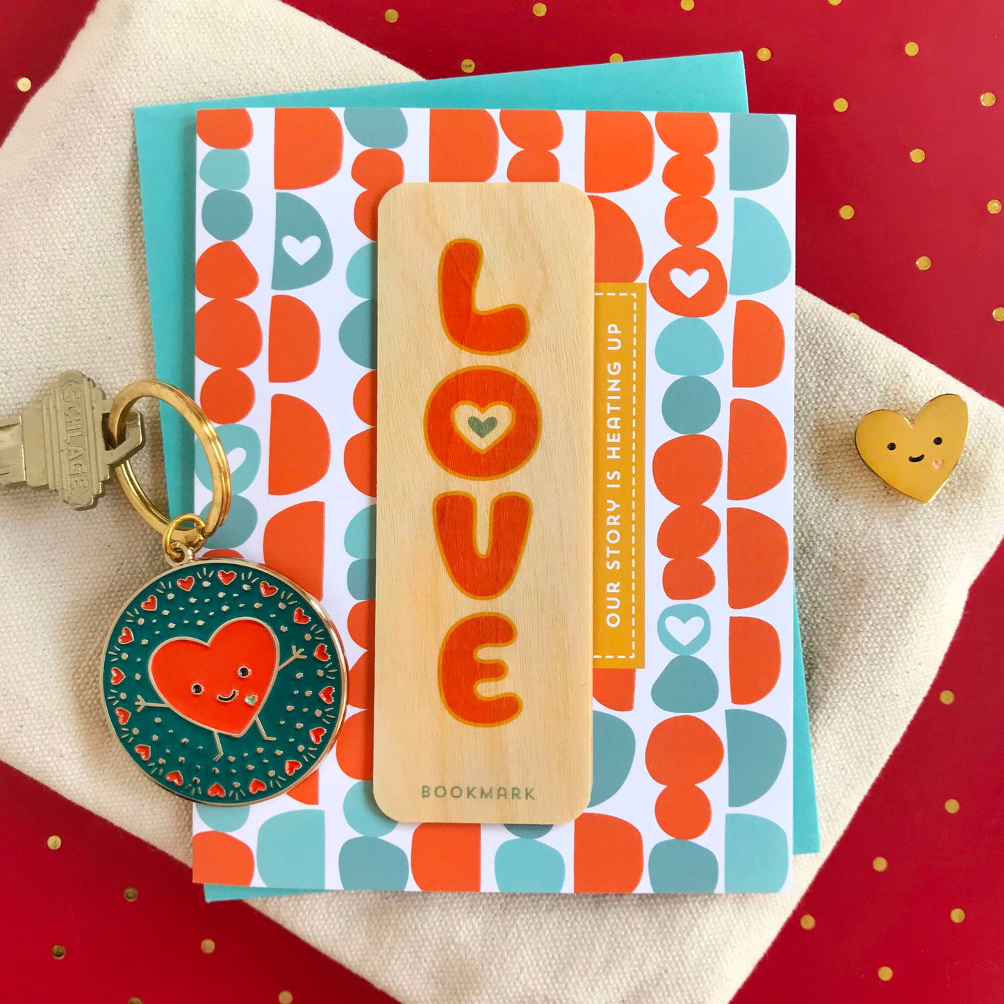 Bookmarks and keychain with heart designs on a patterned card against a red background.