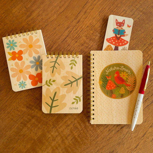 Nature Lover notebook featuring a red bird and forest scene, two mini notepads with wood covers featuring colorful flowers and leaves, a Reading Fox bookmark and a ballpoint pen.