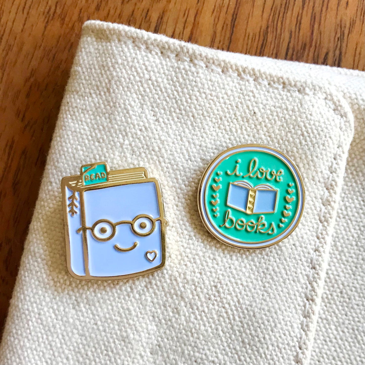 Book Lover enamel pin next to I Love Books enamel pin