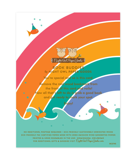 Back of bookmark card. Rainbow and ocean waves background and text that reads "Book Buddies by Night Owl Paper Goods. You're special and so is this card. Remove the real wood bookmark from the front of this card and voila! Now all that's left to do is grab a good book and get ready to mark your spot. Enjoy! No additional postage required. Eco-friendly sustainably harvested wood. Eco-friendly, FSC certified paper made with zero-emission wind generated power. Printed & hand assembled in the USA..."