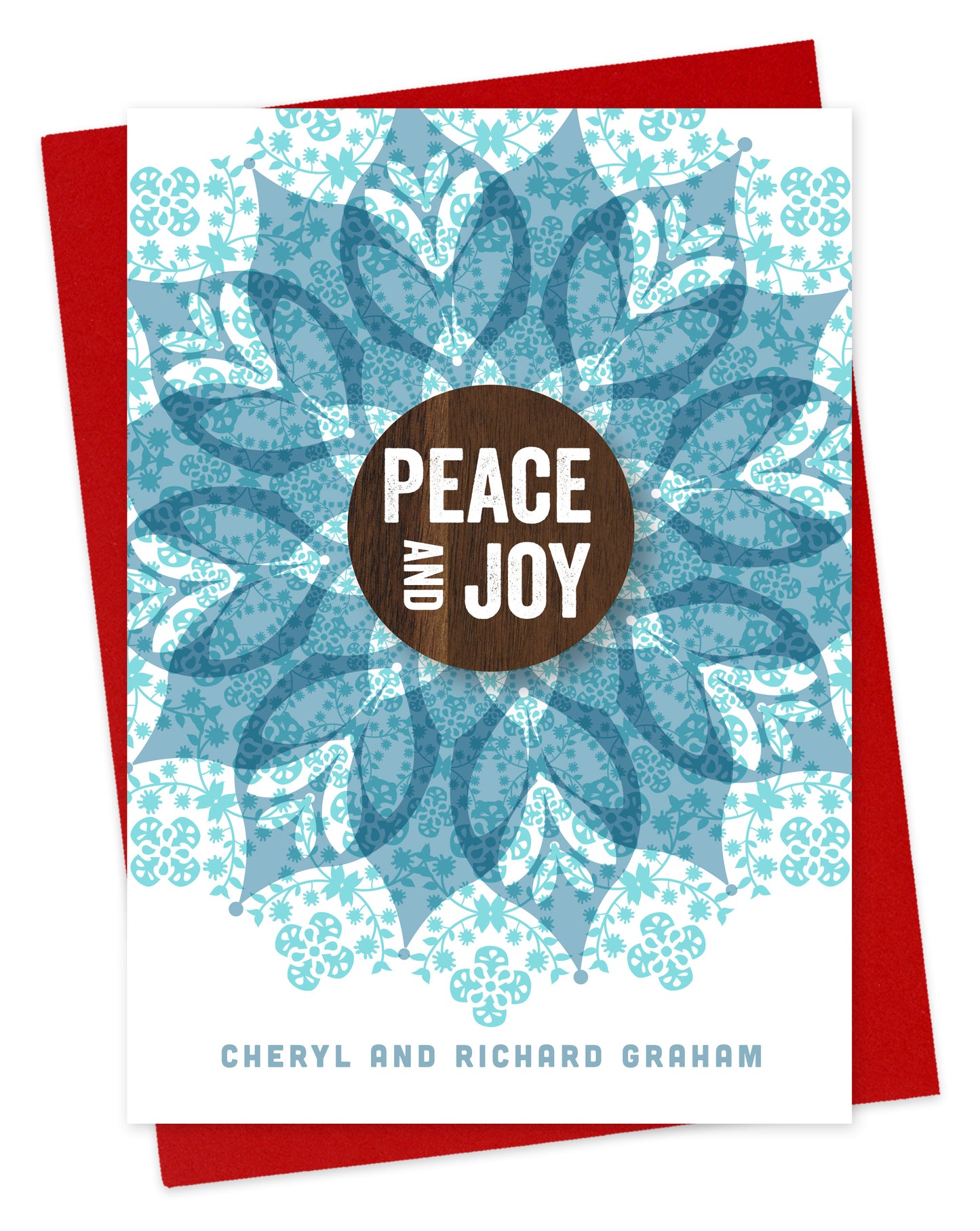 Customizable paper holiday card featuring a detailed blue blossom with a walnut wood grain medallion in the middle that reds “Peace and Joy.” Personal text is at the bottom. Shown with a red envelope.