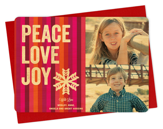 Customizable wood holiday card featuring 2 photos on the right and colorful vertical stripes with “PEACE LOVE JOY” text, a snowflake and a personal greeting on the left. Shown with a red envelope.