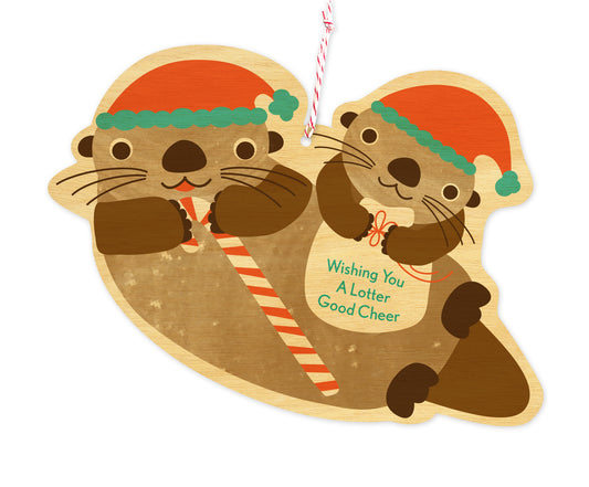 Front of die-cut wood holiday ornament card featuring two otters wearing Santa hats. One is holding a candy cane and the other is holding a bag with "Wishing You A Lotter Good Cheer" text.