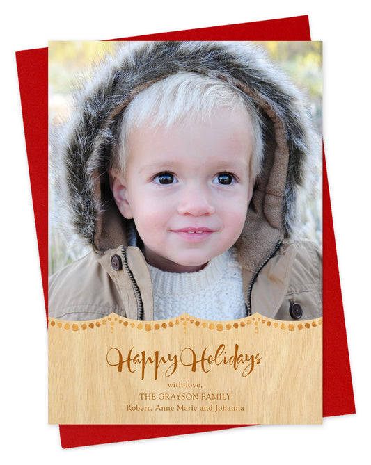 Customizable paper holiday card featuring your photo, a gold dot pattern, 'Happy Holidays' text and a personal greeting on a printed birch wood grain background. Shown on a red envelope.