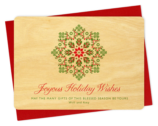 Customizable wood holiday card featuring a red and green snowflake on a birch wood grain background with a personal greeting. Shown with a red envelope.