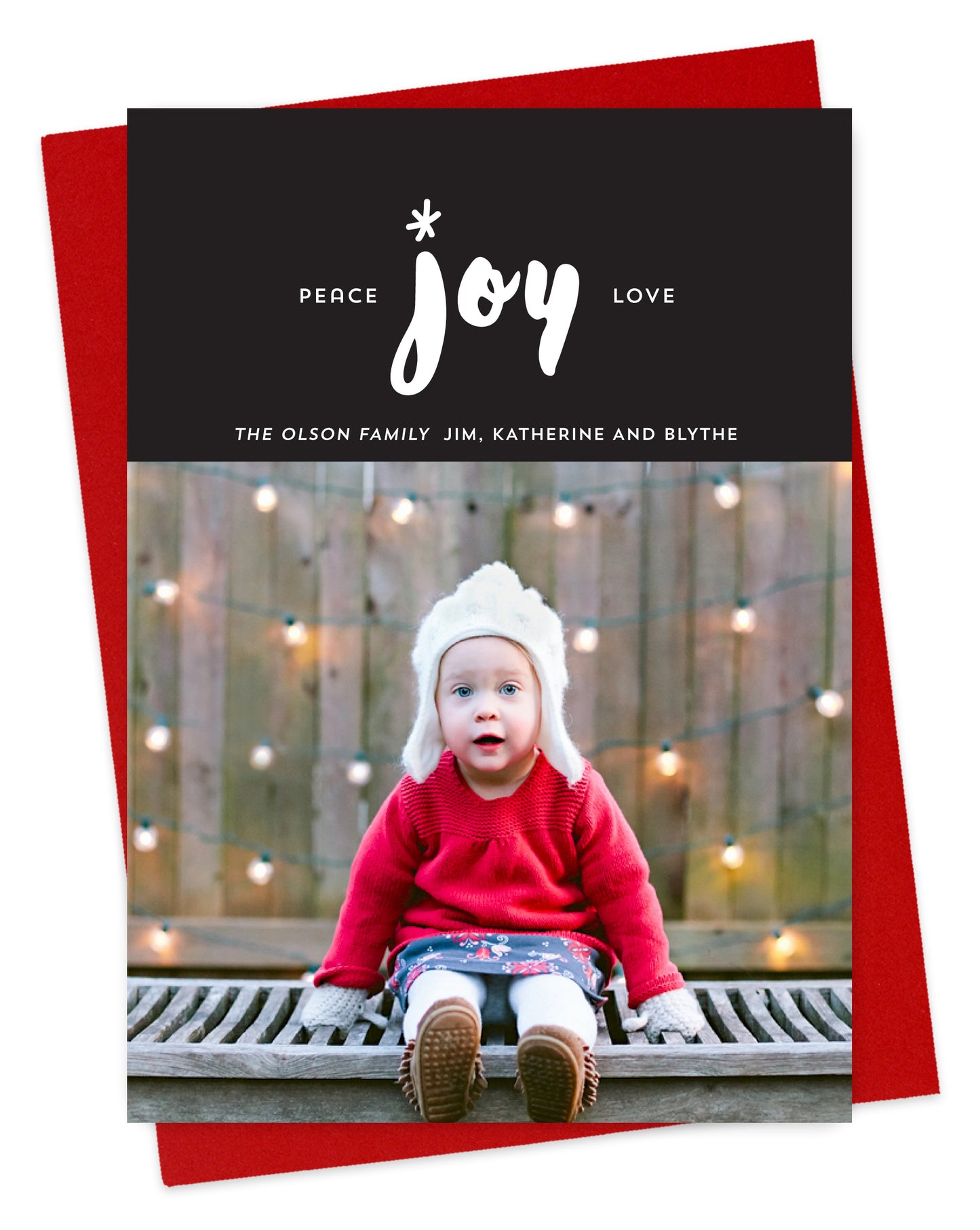 Customizable wood holiday card featuring your photo beneath a striking black banner adorned with “Peace Joy Love” text and a personal greeting. Shown with a red envelope.