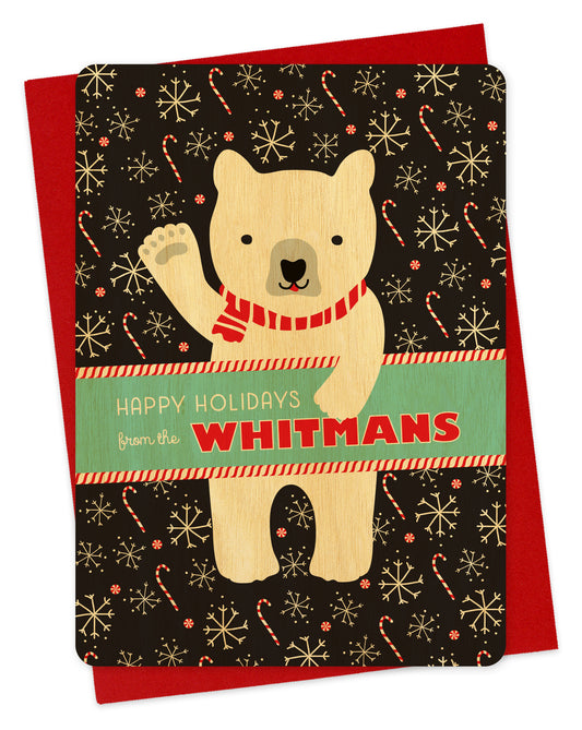 Customizable birch wood holiday card featuring a cheerful polar bear wearing a scarf and waving “Happy Holidays” against a black backdrop with candy canes and snowflakes. A banner across the middle displays a personal greeting. Shown with a red envelope.