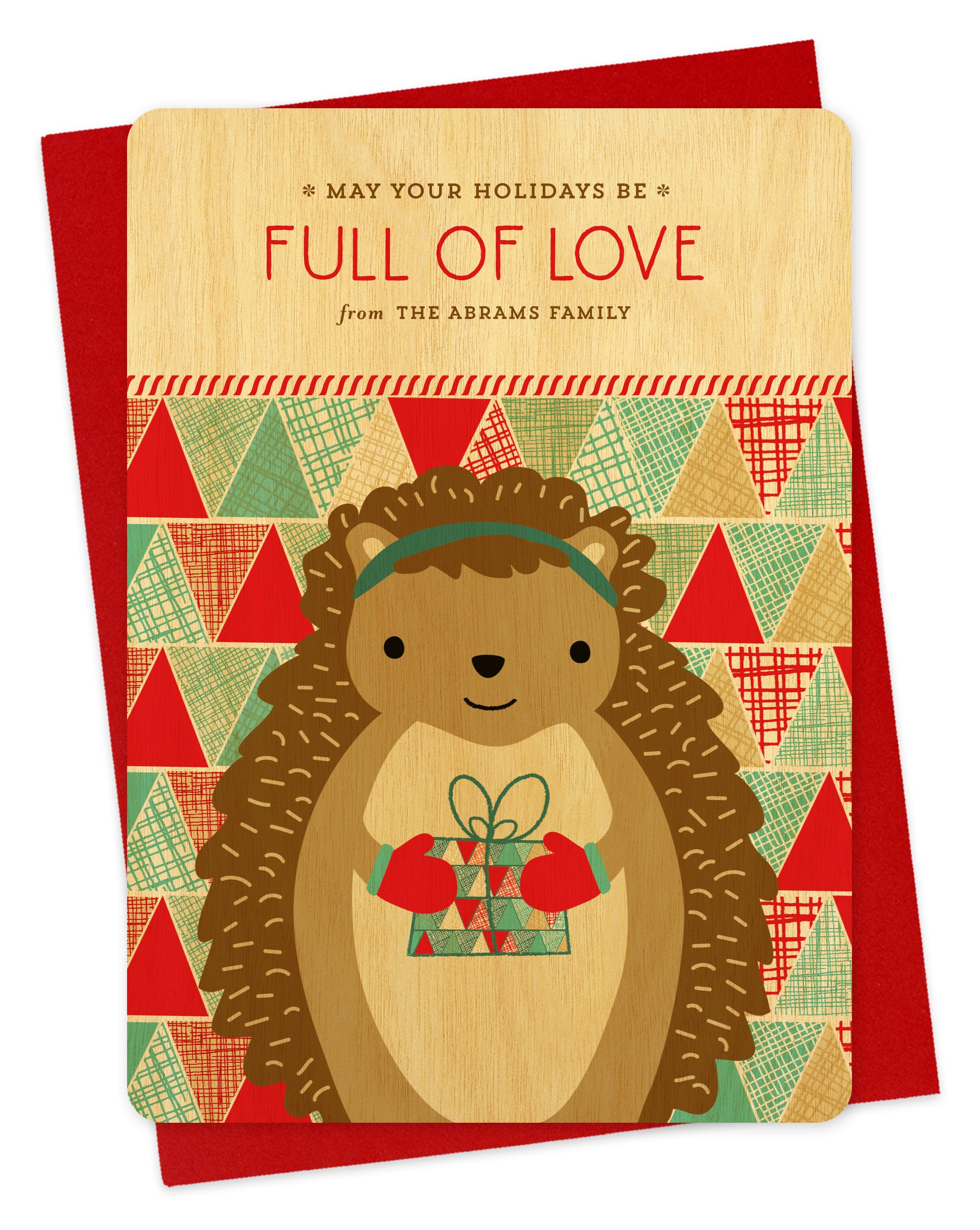 Customizable birch wood holiday card featuring a cute gift-giving hedgehog, “May Your Holidays Be Full Of Love” text and a personal greeting on a colorful, patchwork background. Shown with a red envelope.