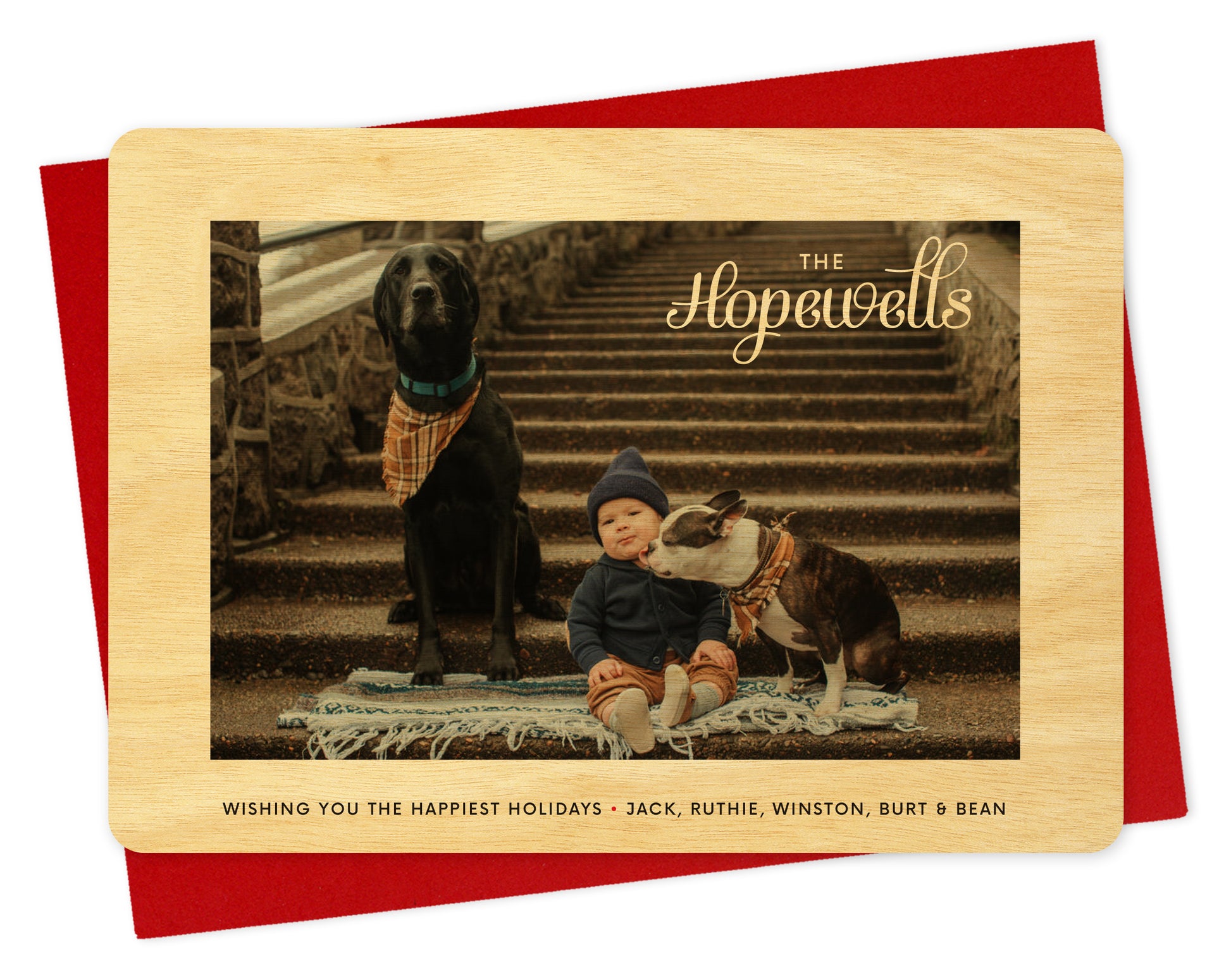 Customizable wood holiday card with a photo framed by a birch wood grain border, a family name in knockout style over the photo and a personal greeting on the bottom. Shown with a red envelope.