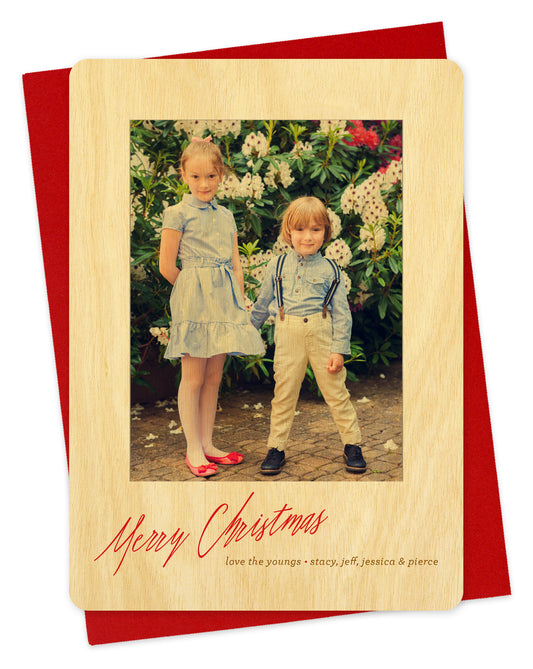 Customizable wood holiday card featuring your photo bordered by birch wood with "Merry Christmas" text near the bottom. Shown with a red envelope.