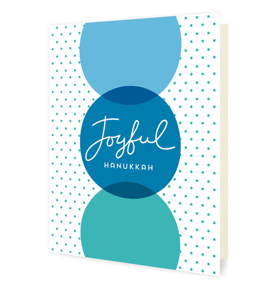 Front of folded holiday card featuring 3 large vertically-oriented dots in various shades of blue with a “Joyful Hanukkah" greeting in the middle dot. The background is white with small aqua blue dots.