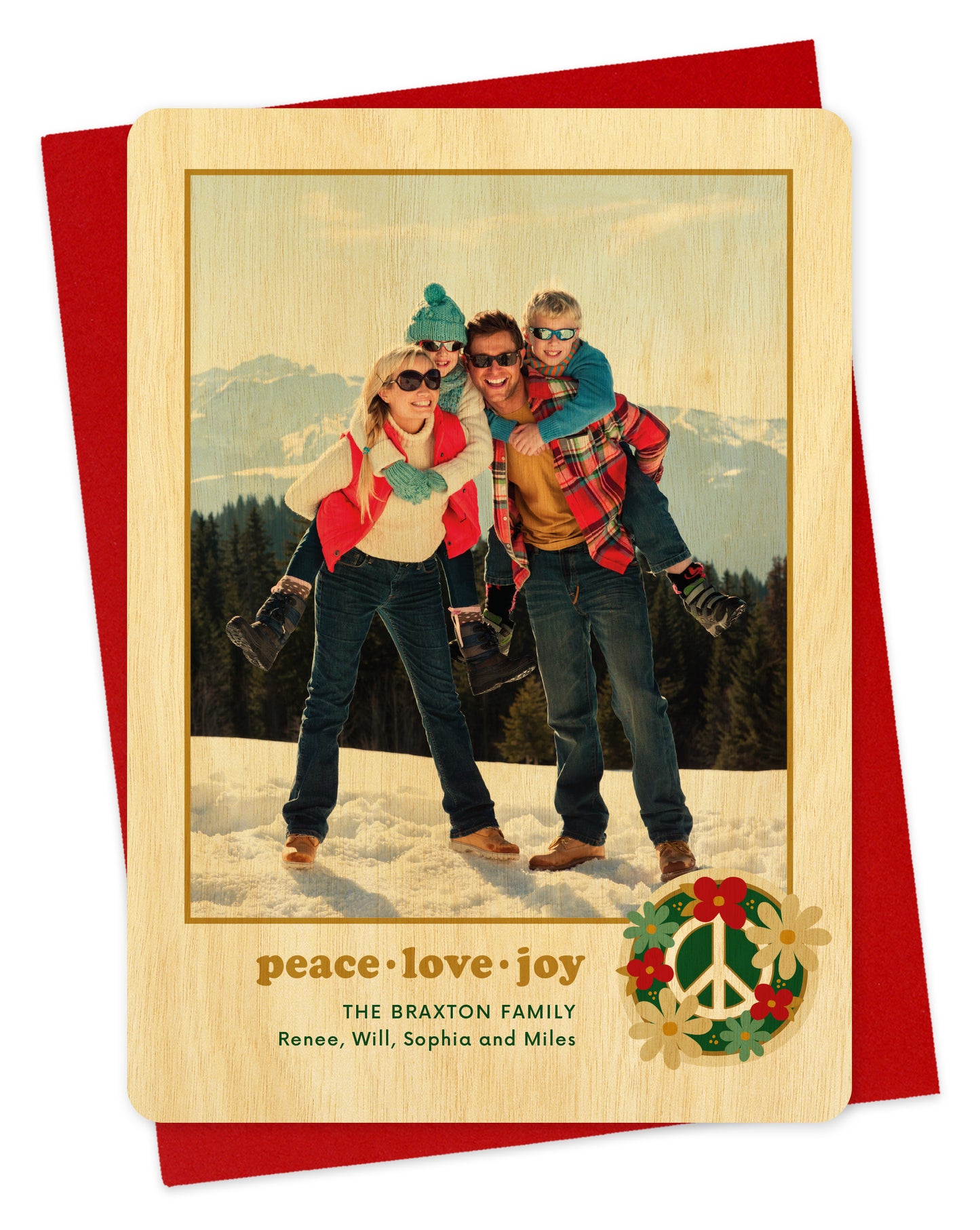 Customizable wood holiday card featuring a family photo with “peace love joy” text and a peace sign surrounded by flowers near the bottom, shown with a red envelope.