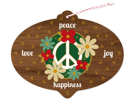 Front of bulb-shaped paper holiday ornament card with floral peace sign and “peace, love, joy, happiness” text on a printed walnut wood grain background.