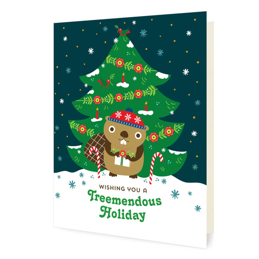 Front of folded Christmas card featuring a cheerful beaver in front of a decorated Christmas tree and snowy skies outside with the pun “Wishing You a Treemendous Holiday.”