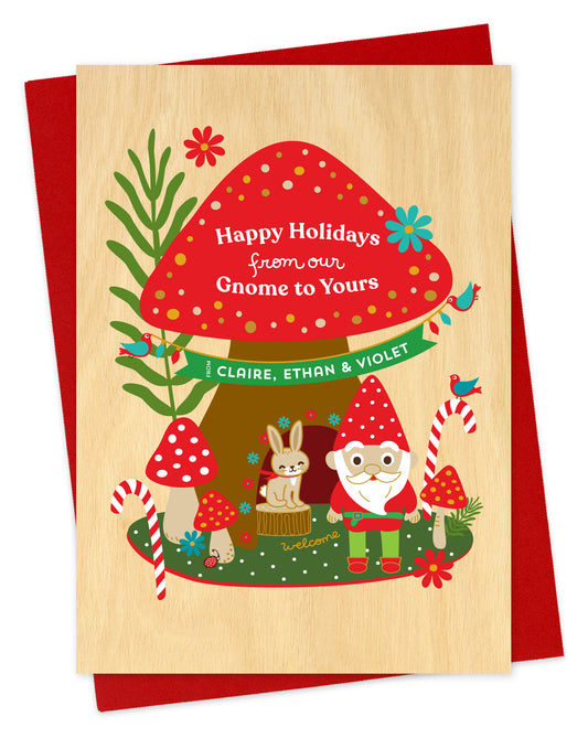 Customizable paper holiday card with a woodland gnome, mushrooms and rabbit illustration and 'Happy Holidays from our Gnome to Yours' text on a red envelope.