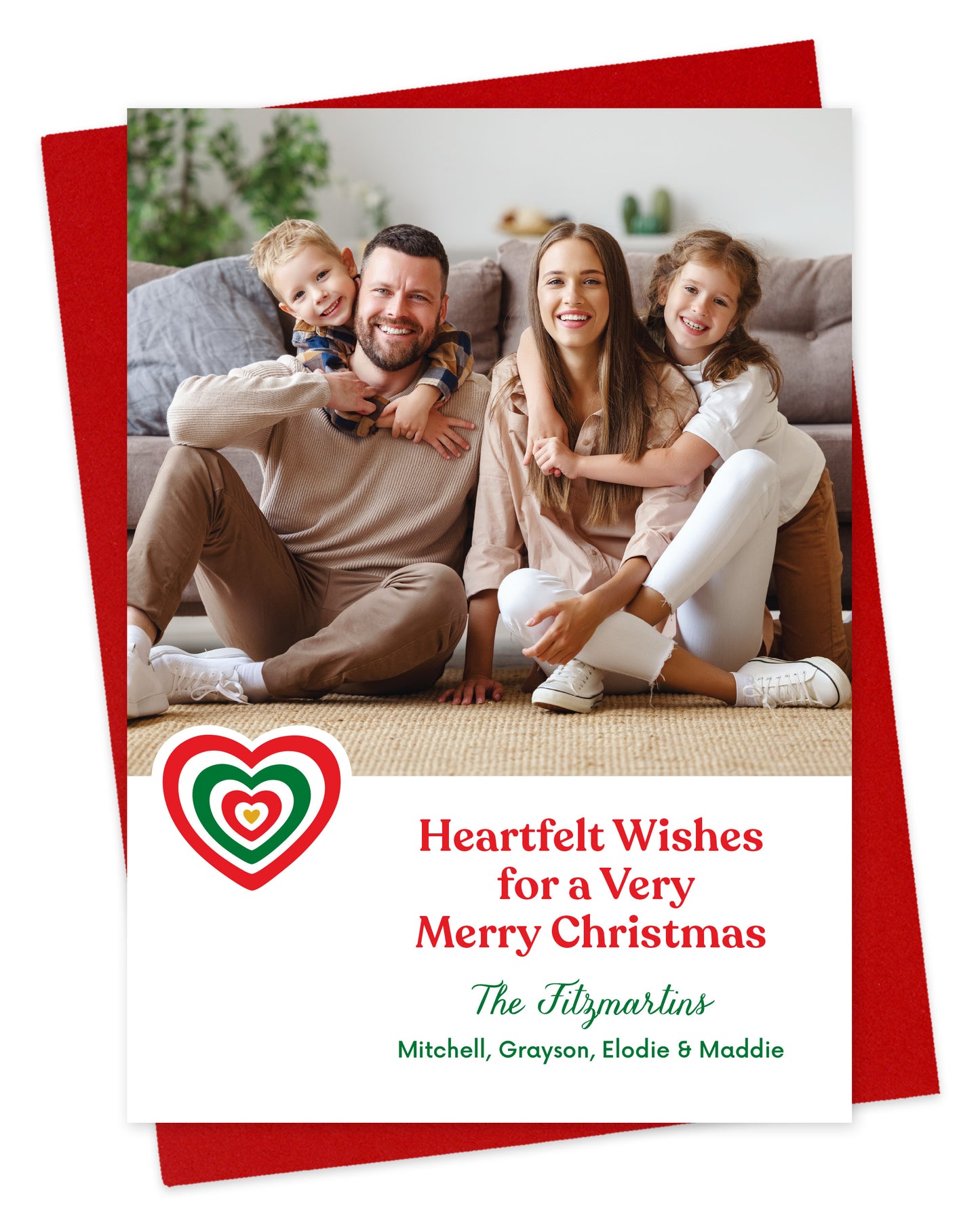 Customizable paper holiday card featuring a family photo, a red and green heart, 'Heartfelt Wishes for a Very Merry Christmas' text and a personal greeting. Shown on a red envelope.