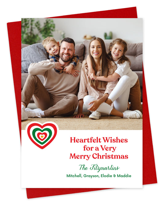 Customizable paper holiday card featuring a family photo, a red and green heart, 'Heartfelt Wishes for a Very Merry Christmas' text and a personal greeting. Shown on a red envelope.