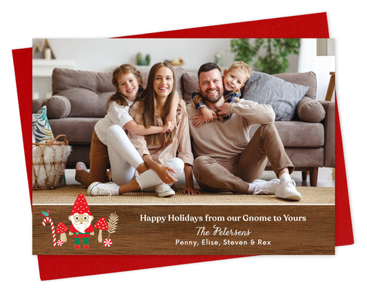 Customizable paper holiday card  featuring a landscape family photo above a printed walnut wood grain border adorned with a cheerful gnome. Text reads 'Happy Holidays from our Gnome to Yours' along with a personal greeting. Shown on a red envelope.