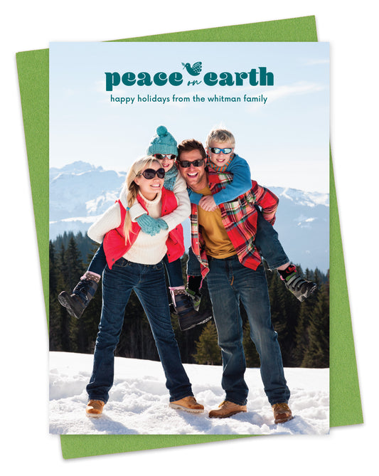 Customizable paper holiday card featuring a full portrait photo with the words “Peace on Earth” and a dove carrying an olive branch near the top, shown with a green envelope.