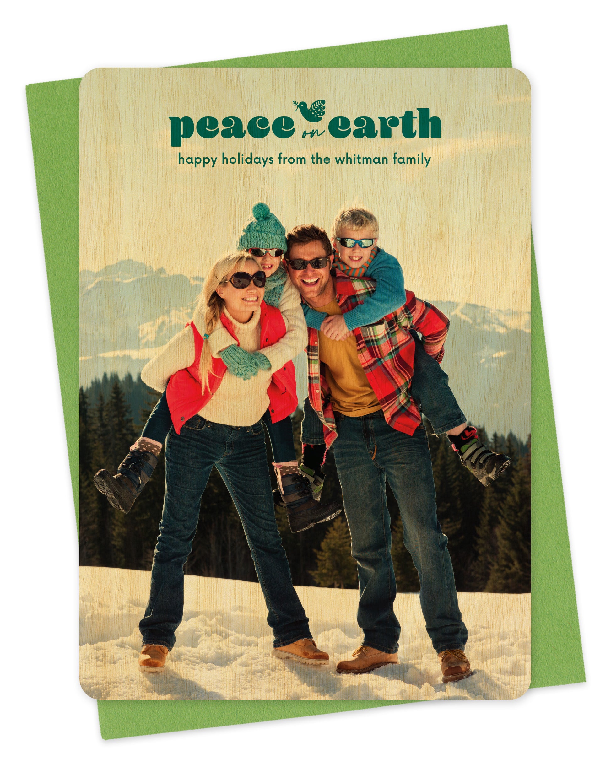 Customizable wood holiday card featuring a full portrait photo with the words “Peace on Earth” and a dove carrying an olive branch near the top, shown with a green envelope.