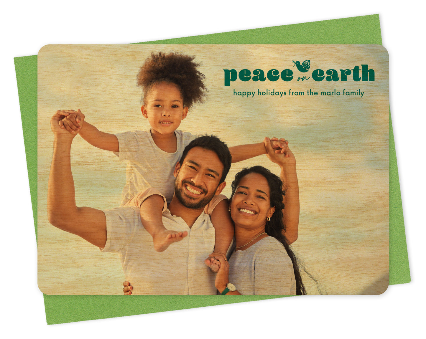 Customizable wood holiday card featuring a full landscape photo with the words “Peace on Earth” and a dove carrying an olive branch near the top, shown with a green envelope.