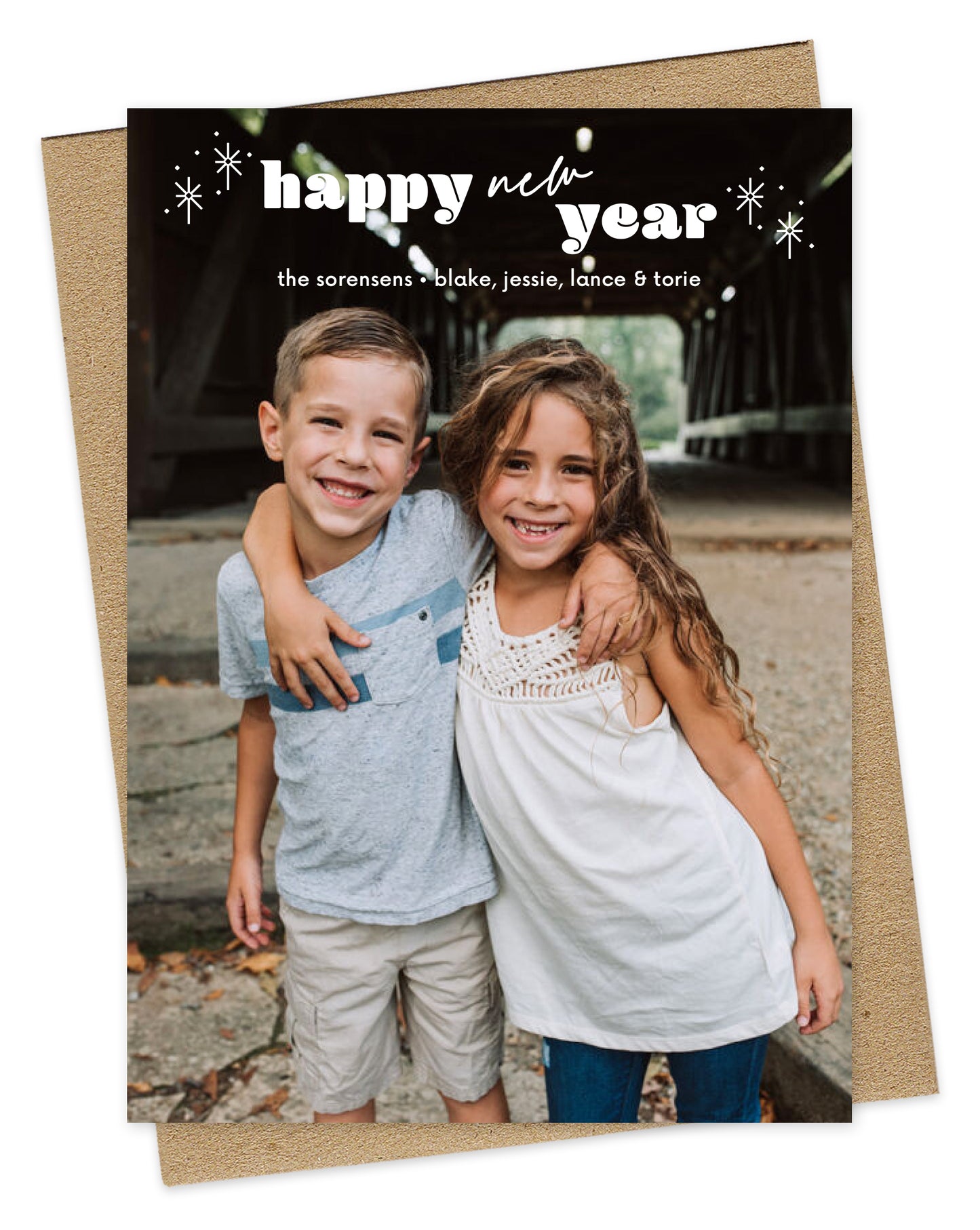 Customizable paper holiday card featuring a full photo with "happy new year” text, sparkle illustration and personal greeting near the top. Shown with a kraft envelope.
