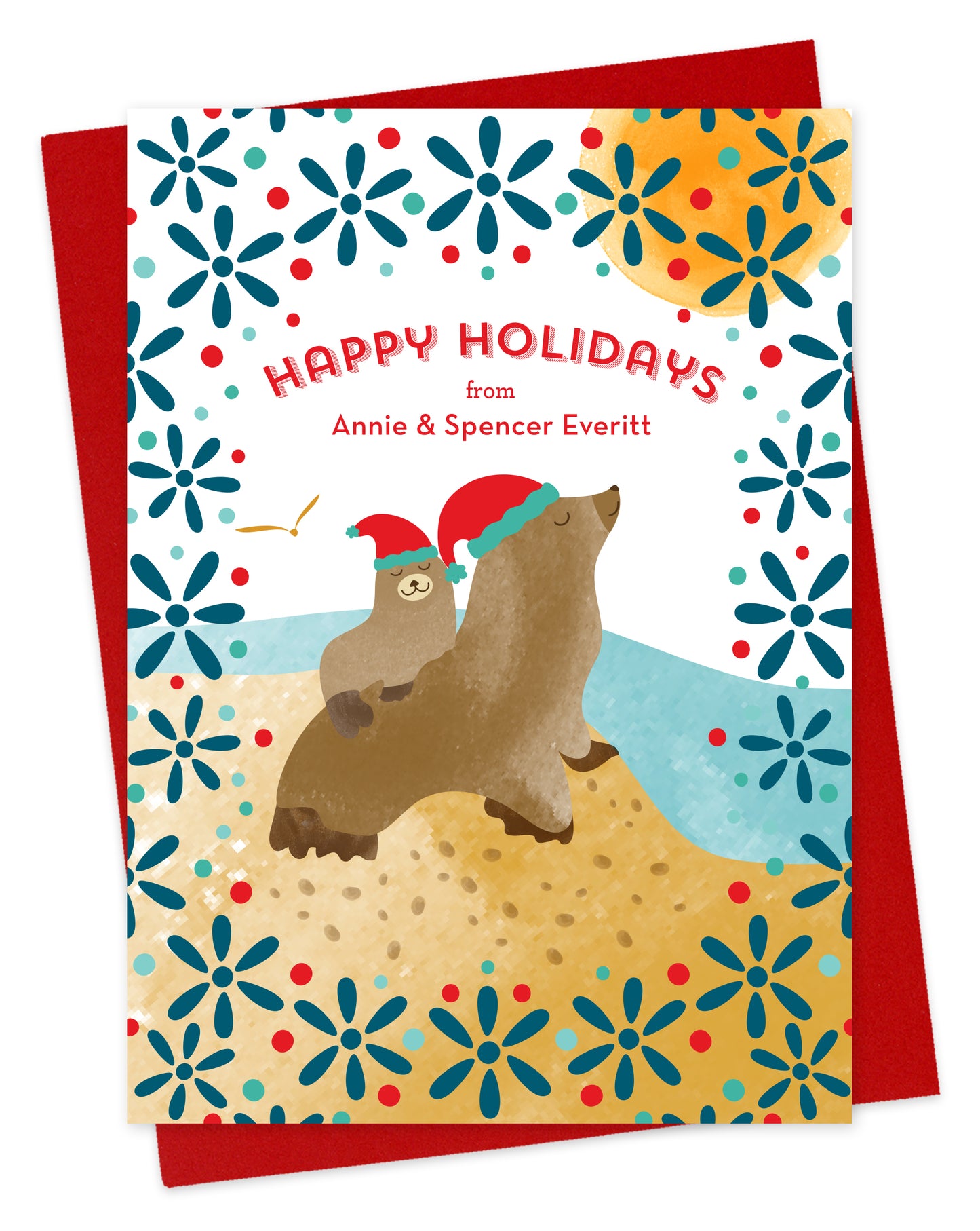 Customizable paper holiday card featuring two illustrated sea lions in Santa hats, near the water with a festive patterned background. “Happy Holidays” sentiment along with a personal greeting. Shown with a red envelope.