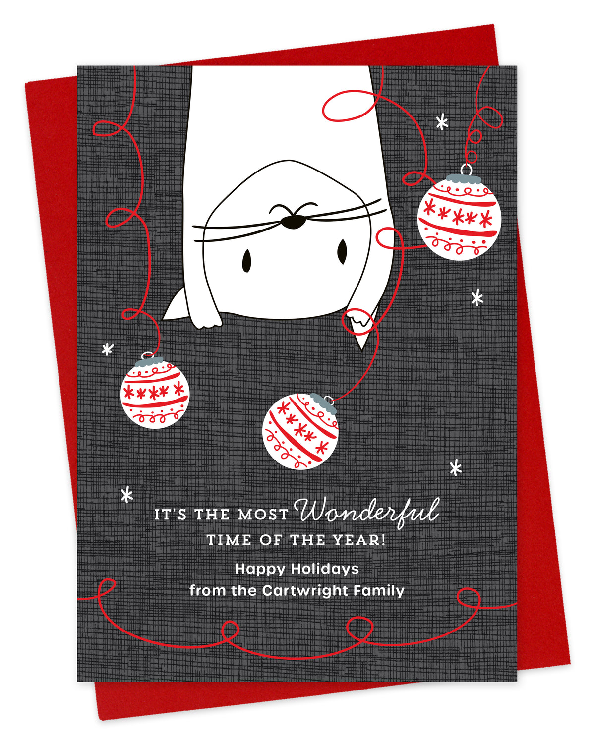 Customizable paper holiday card featuring a playful upside-down white cat surrounded by festive ornaments, a "It's the most wonderful time of the year!" sentiment and a personal greeting. The card background is a grey crosshatch pattern. Pictured with a red envelope.
