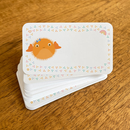 A stack of small white Puffer Fish note cards with rounded corners, featuring a cute orange puffer fish surrounded by colorful confetti-like dots, with small heart, rainbow and star details.