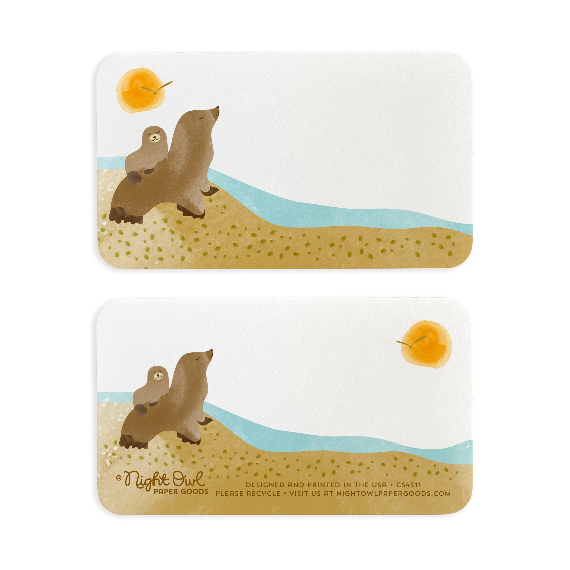 A small white Sea Lions note card shown front and back. The front features cute sea lions on a sandy beach beside blue ocean water with a golden sun overhead, while the back has a coordinating sea lion design and small text at the bottom that reads "Night Owl Paper Goods - Designed and printed in the USA - Please recycle - Visit us at nightowlpapergoods.com." Both sides include space for a handwritten note.