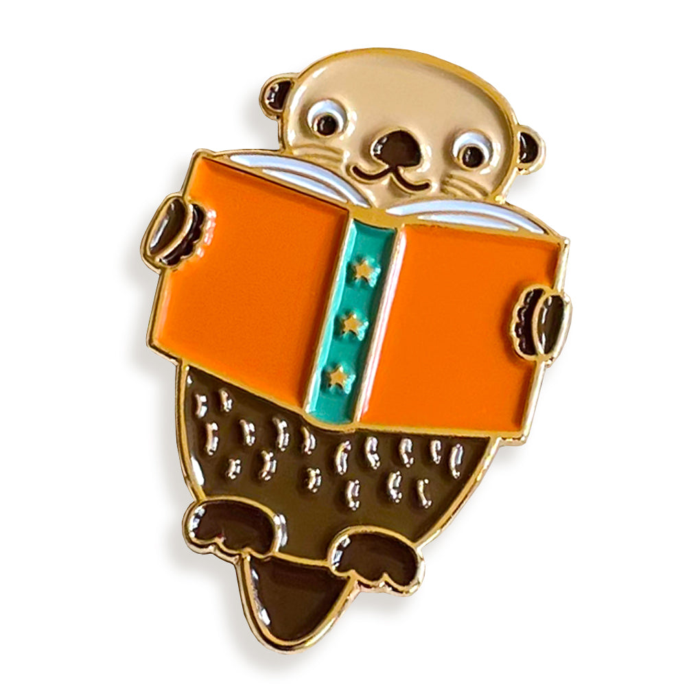 Enamel pin of an otter reading a book