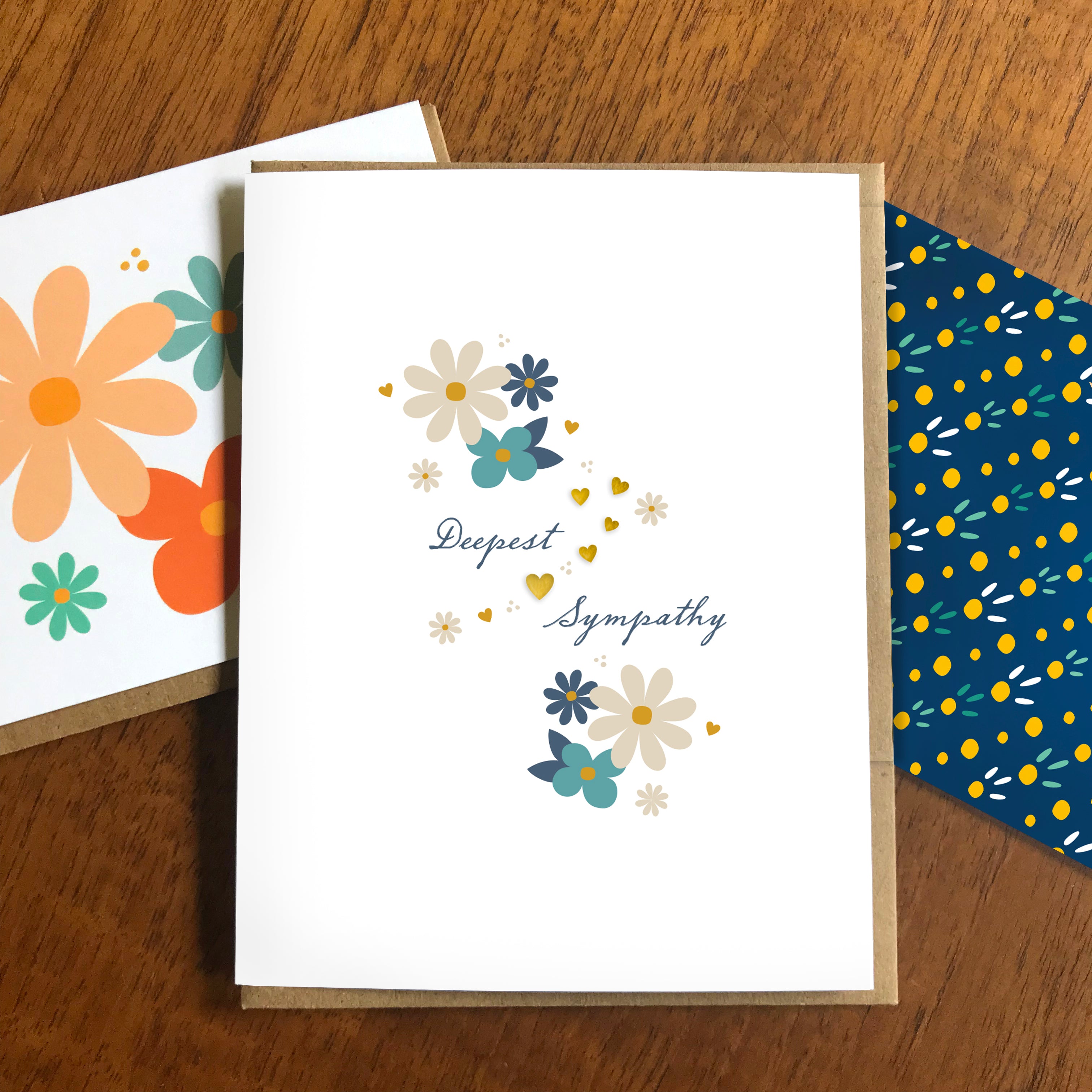 Sympathy greeting card with floral design, gold foil and 'Deepest Sympathy' text, displayed on a wooden surface.