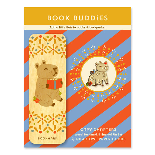 Capy Chapters Book Buddies wood bookmark and enamel pin gift set featuring a capybara holding a book on a wooden bookmark and a coordinating capybara enamel pin on a colorful striped backer card.