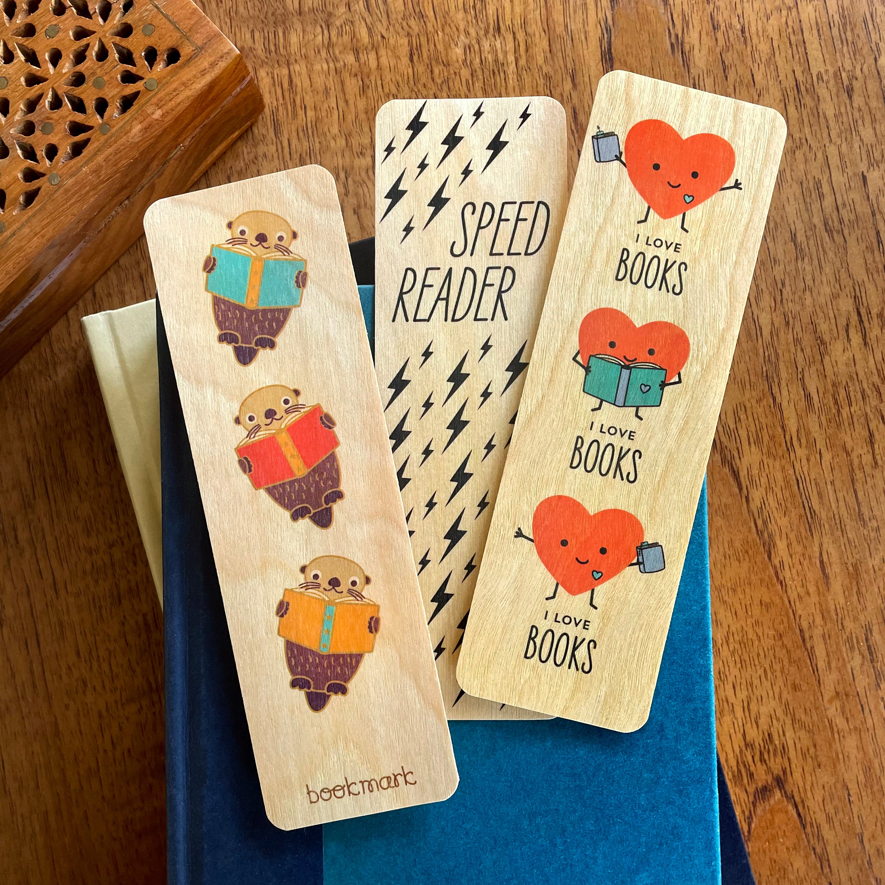 Three wooden bookmarks with cute designs displayed on top of a book