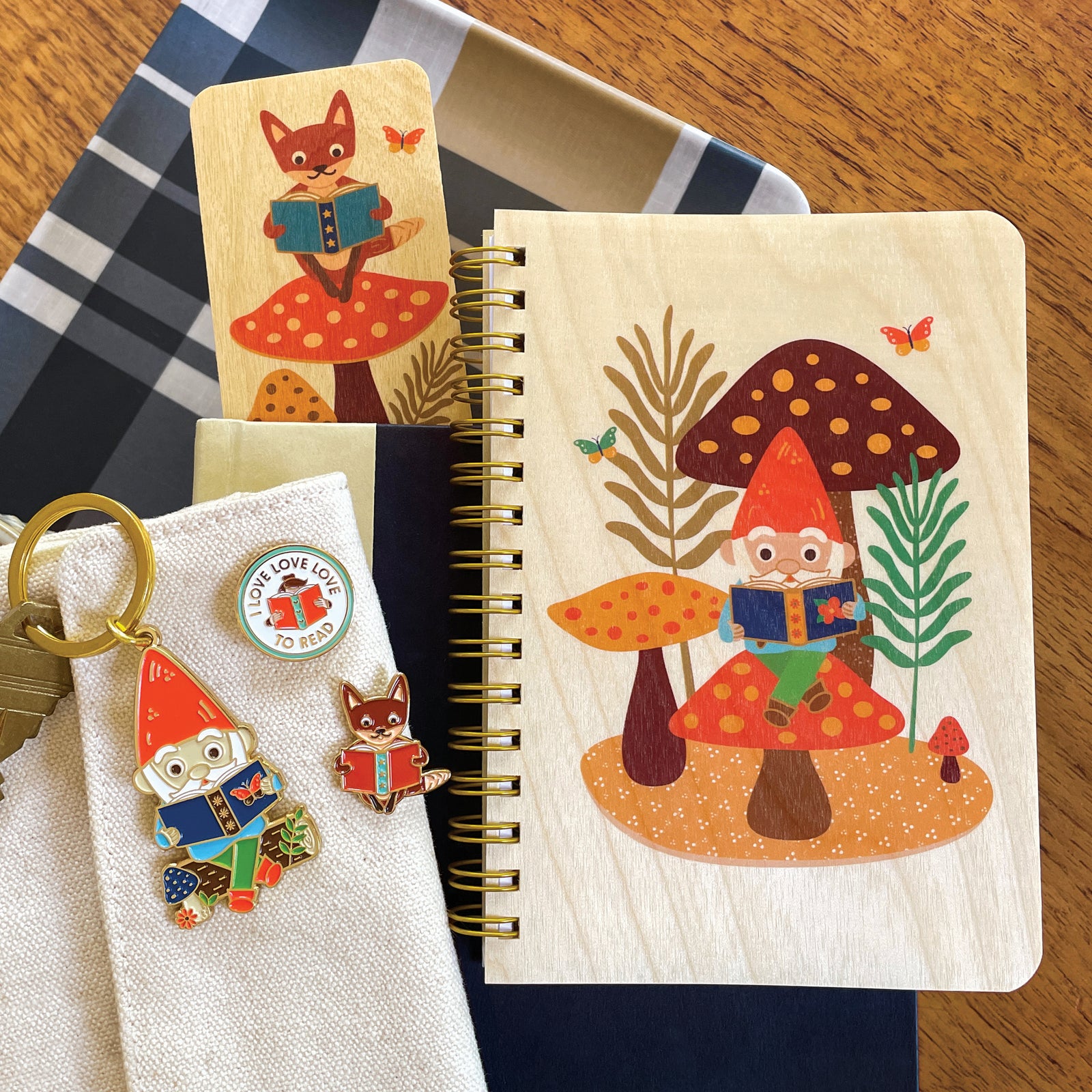 Collection of Book Lover products, including Reading Gnome wood notebook and keychain, Love to Read and Reading Fox enamel pins and Reading Fox wood bookmark.