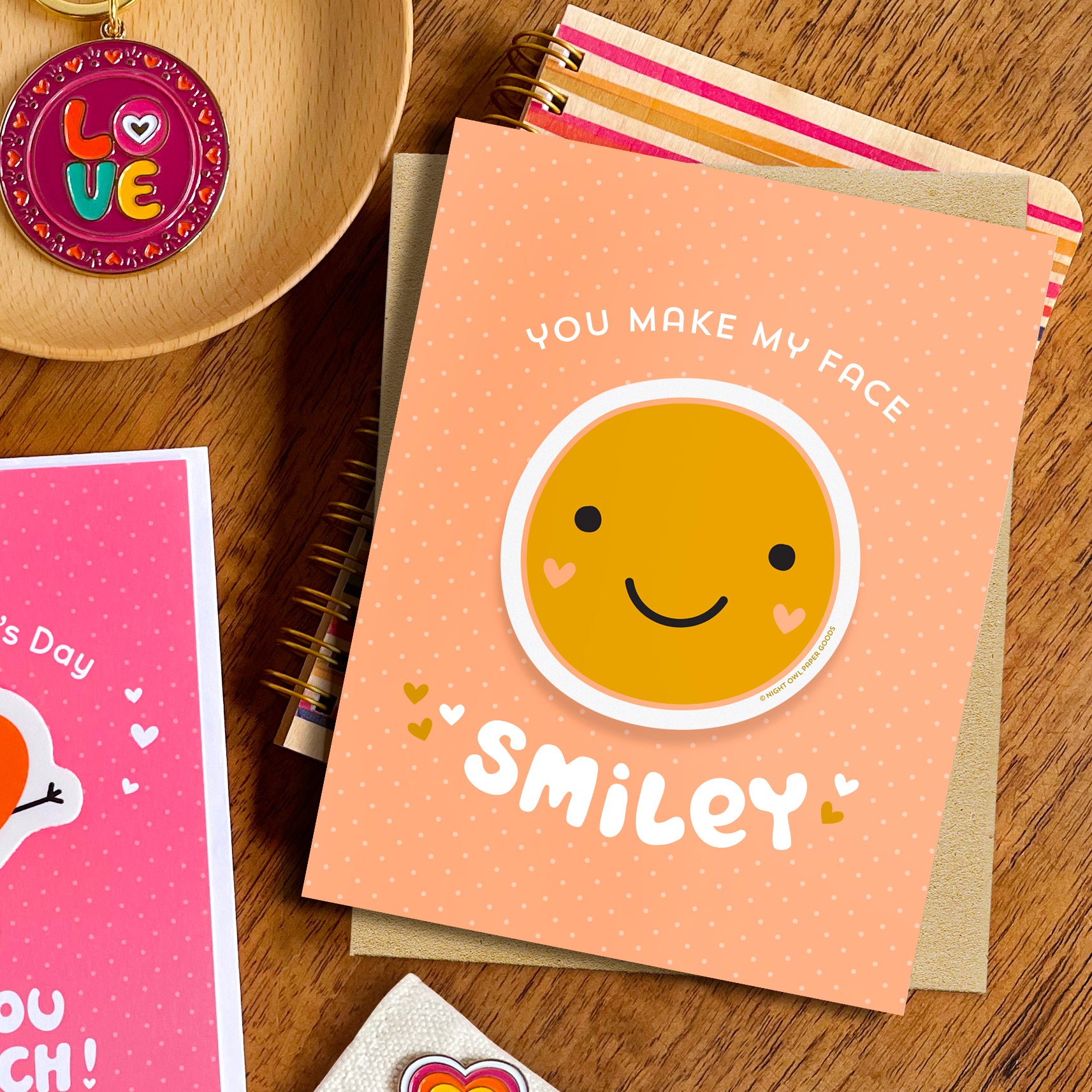 Greeting card with smiley face removable vinyl sticker and text 'You make my face smiley' displayed on a wooden surface.