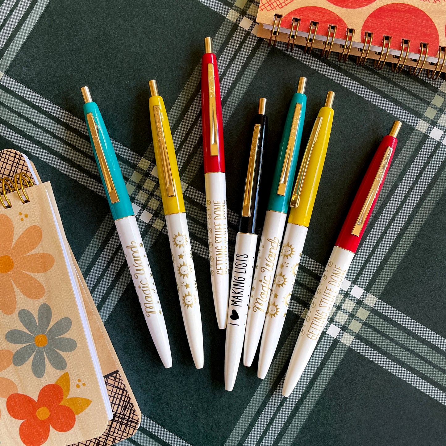 Click pens with aqua, red, yellow and black caps with gold or black messages on the barrel. Fun styles read "Magic Wand", "Getting Stuff Done", I (heart) Making Lists" and a pen with sunny happy faces and shooting stars.