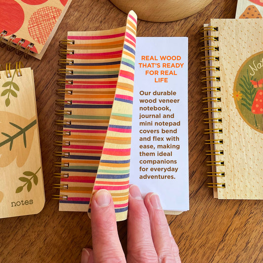 Party Lines Wood Notebook with front cover curled back, showing the flexibility of the wood. Text reads REAL WOOD THAT'S READY FOR REAL LIFE - Our durable wood veneer notebook, journal and mini notepad covers bend and flex with ease, making them ideal companions for everyday adventures.