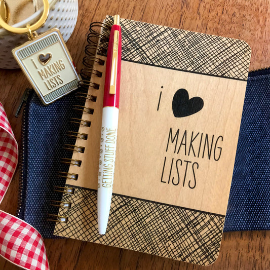 Durable, wood notebook with 'I ❤️ Making Lists' on cover in black with crosshatch pattern. Pen reads 'Getting Stuff Done'. Gold keychain features heart shape die-cut.