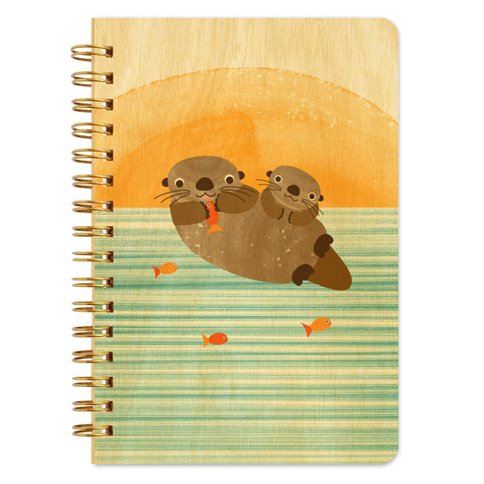 Spiral-bound wood notebook with birch wood covers featuring two playful otters swimming in water alongside orange fish.