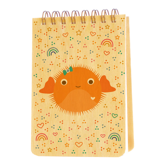 Mini notepad with birch wood covers, spiral binding at top and a cute orange puffer fish surrounded by small heart, rainbow, star and dot designs.