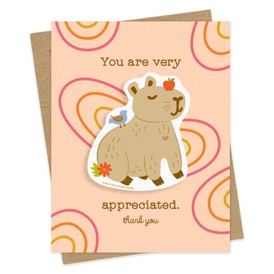 Thank You card with a removable vinyl sticker of a content capybara and the message “You are very appreciated. Thank You”  on a pink background. Pictured with a kraft envelope.